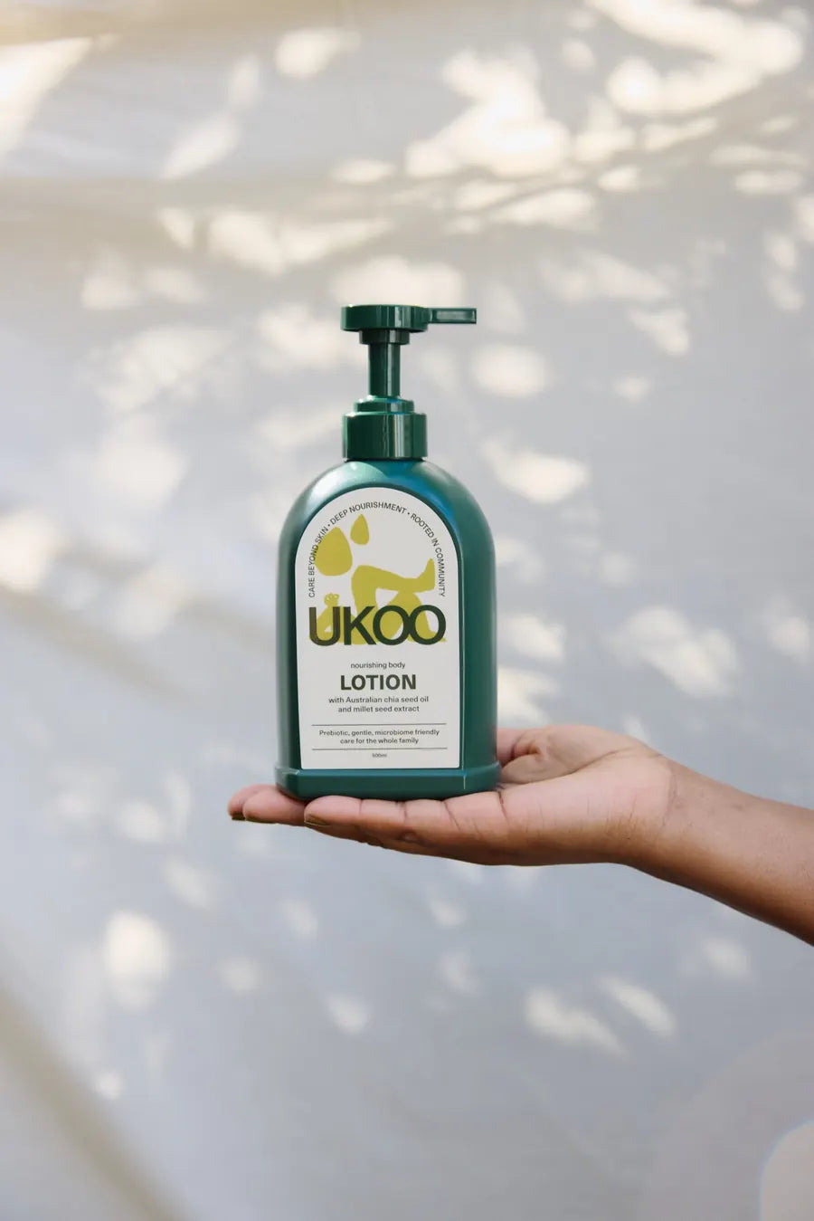 An open hand holding the lotion bottle in dappled light