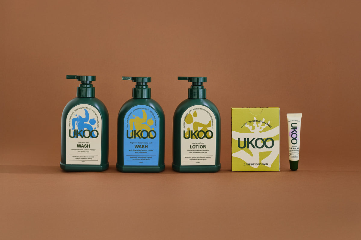 UKOO body wash, fragrance-free body wash and body lotion with conversation cards and lip balm on a terracotta ground